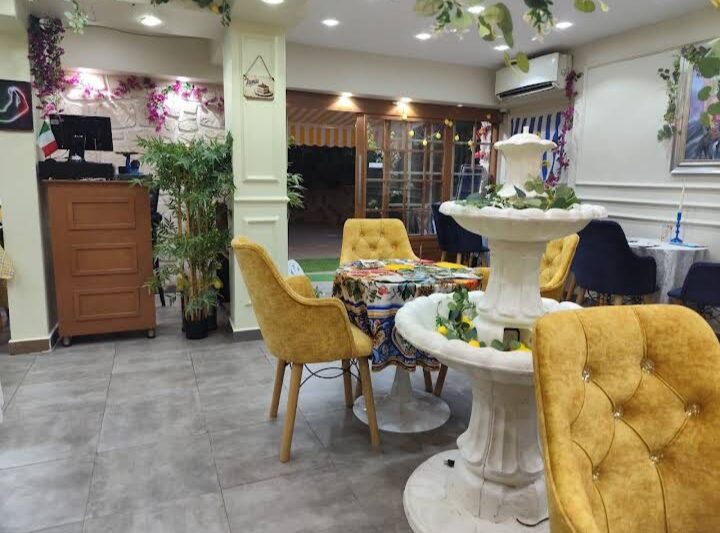 Intérieur chaleureux du restaurant Dolce Vita Brunchy avec fauteuils moutarde et fontaine